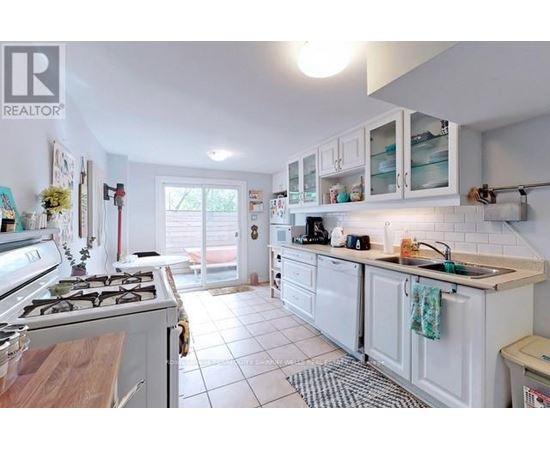 A white kitchen with a stove top oven and a sink.
