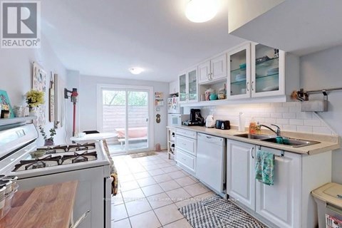 A white kitchen with a stove top oven and a sink.