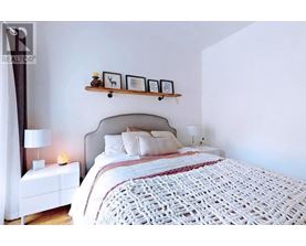 A bedroom with a large bed and a nightstand with a lamp.