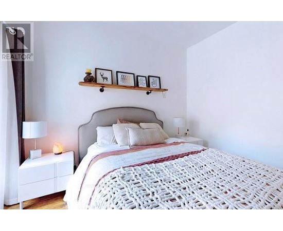 A bedroom with a large bed and a nightstand with a lamp.