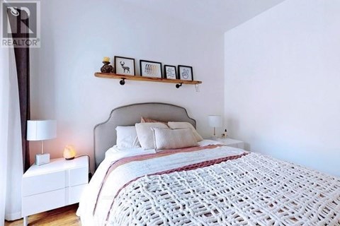 A bedroom with a large bed and a nightstand with a lamp.