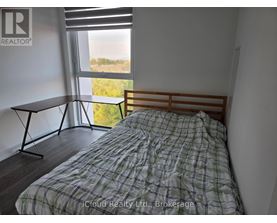 A bedroom with a bed, a table, and a window with a view of the outdoors.