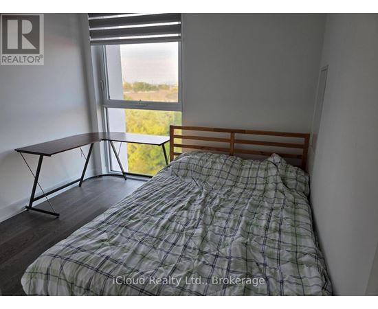 A bedroom with a bed, a table, and a window with a view of the outdoors.