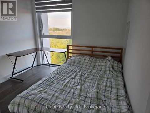 A bedroom with a bed, a table, and a window with a view of the outdoors.