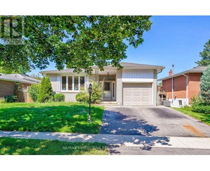 A house with a driveway and a garage is surrounded by greenery.