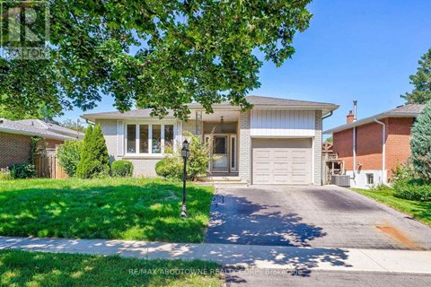 A house with a driveway and a garage is surrounded by greenery.