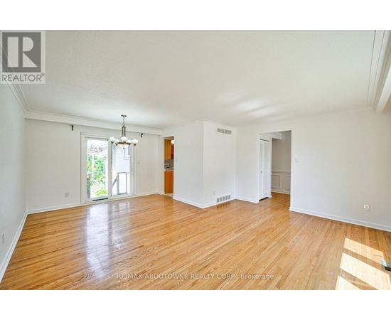 A large empty room with wooden floors and white walls.