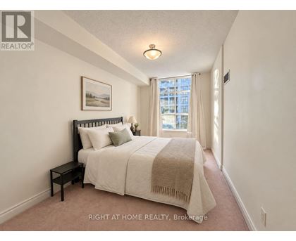 A bedroom with a bed, nightstand, and window.