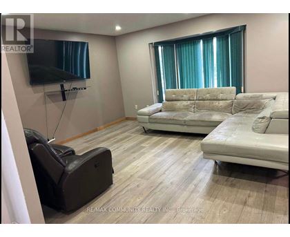 A living room with a white couch and a black leather chair.