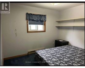 A bedroom with a bed, nightstand, and window.
