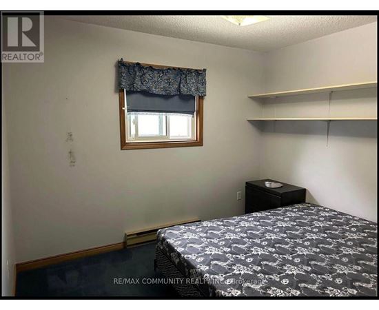A bedroom with a bed, nightstand, and window.