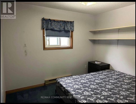 A bedroom with a bed, nightstand, and window.