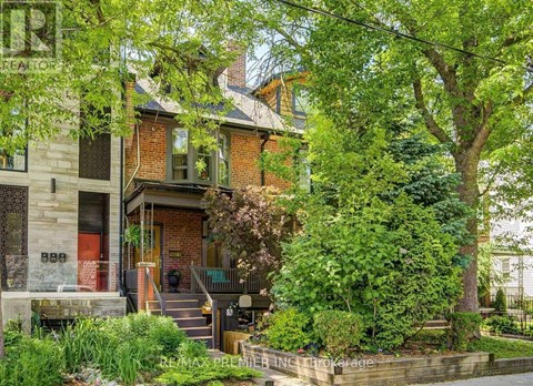 A house with a red door is surrounded by greenery.