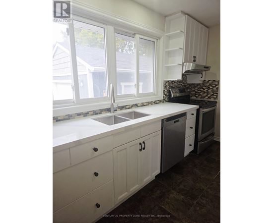 A kitchen with white cabinets and a black and white tiled backsplash.