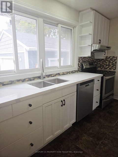A kitchen with white cabinets and a black and white tiled backsplash.