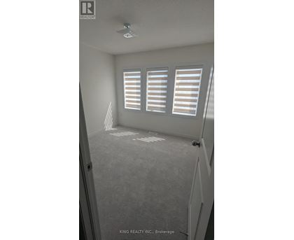 A room with a carpeted floor and a window with blinds.