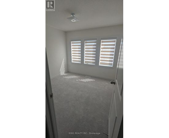 A room with a carpeted floor and a window with blinds.