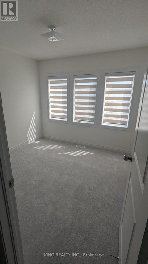 A room with a carpeted floor and a window with blinds.