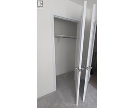 A white closet with a shelf and a white door.
