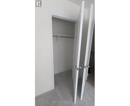 A white closet with a shelf and a white door.