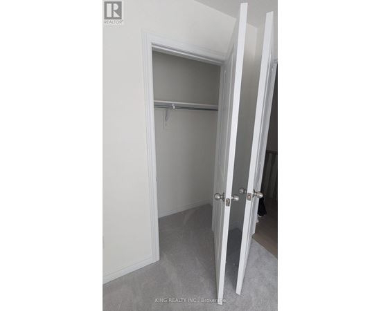 A white closet with a shelf and a white door.