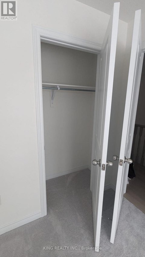 A white closet with a shelf and a white door.