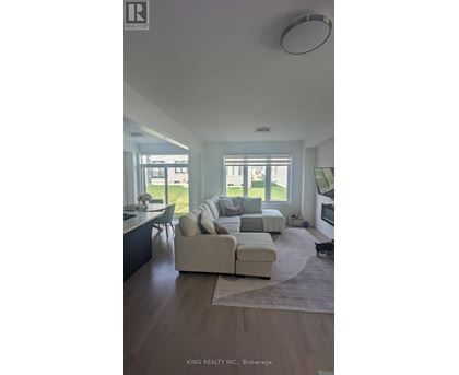 A modern living room with a large sectional sofa and a kitchen area in the background.