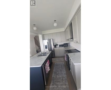 A kitchen with white cabinets and a marble countertop.