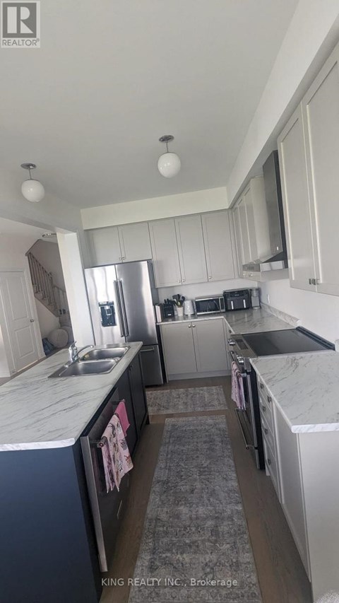A kitchen with white cabinets and a marble countertop.