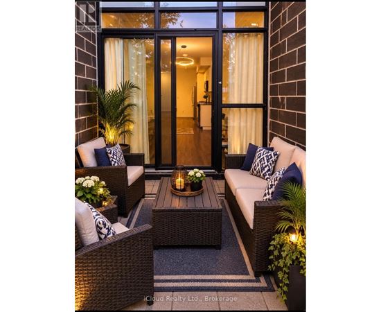 A cozy outdoor seating area with a wicker sofa, chairs, and a table with a lit candle.