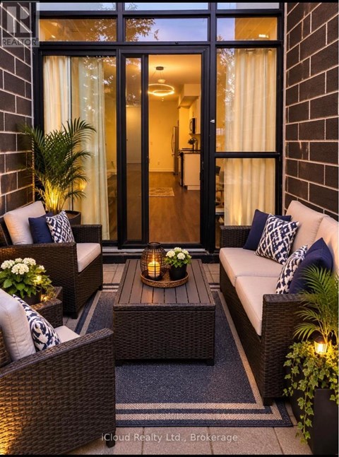 A cozy outdoor seating area with a wicker sofa, chairs, and a table with a lit candle.