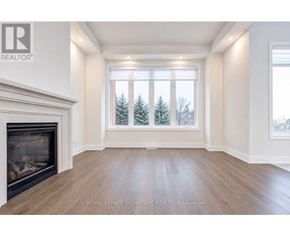 A large, empty room with a fireplace and a view of trees outside the window.