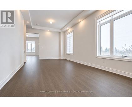 A spacious room with wooden flooring and white walls, with a window showing a snowy landscape outside.