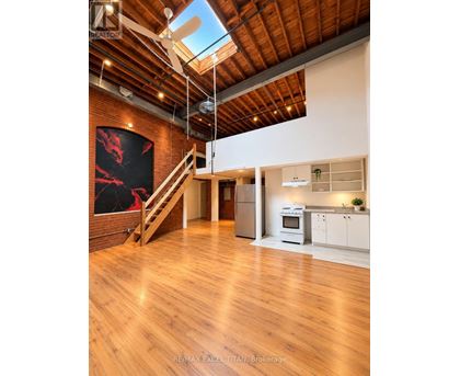 A spacious open plan living and kitchen area with wooden floors and a skylight.