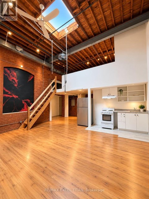 A spacious open plan living and kitchen area with wooden floors and a skylight.