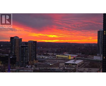 A cityscape at sunset with the sun setting behind the buildings.