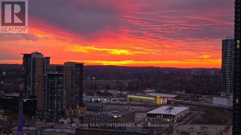 A cityscape at sunset with the sun setting behind the buildings.