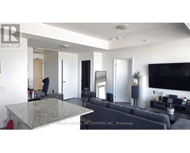 A living room with a grey couch and a flat screen TV mounted on the wall.