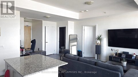 A living room with a grey couch and a flat screen TV mounted on the wall.