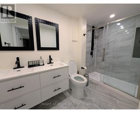 A bathroom with a toilet, sink, and mirror.