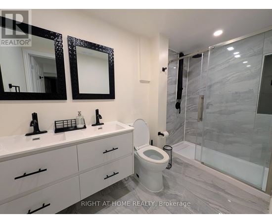 A bathroom with a toilet, sink, and mirror.