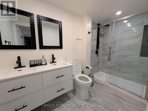 A bathroom with a toilet, sink, and mirror.