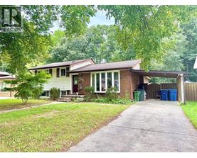 A house with a driveway and a green trash can.