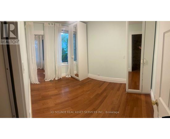 A room with white walls and wooden flooring, with a door on the right side.