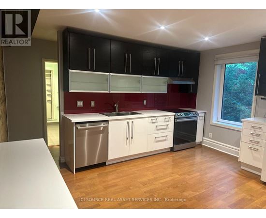 A kitchen with black cabinets and a red backsplash.