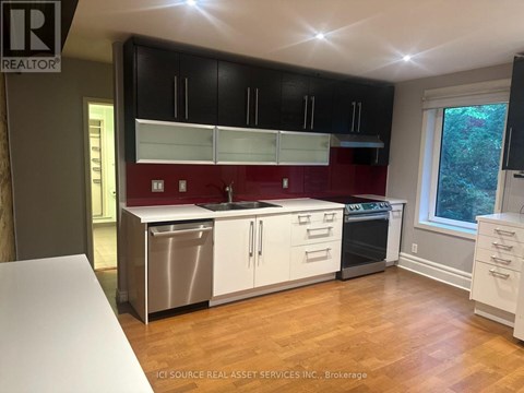 A kitchen with black cabinets and a red backsplash.