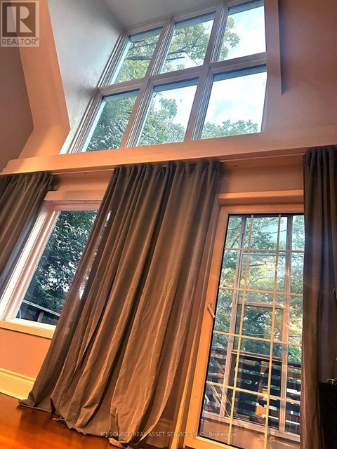 A window with a view of trees and a balcony with a railing.