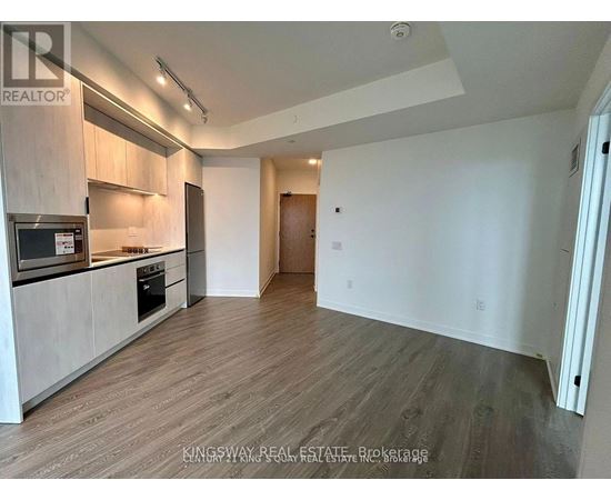 A spacious kitchen with wooden flooring and modern appliances.