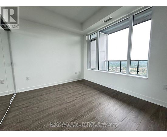 A room with a large window and wooden flooring.