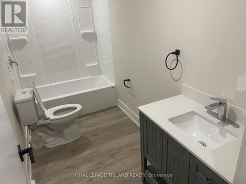 A white sink is on a counter next to a toilet in a bathroom.